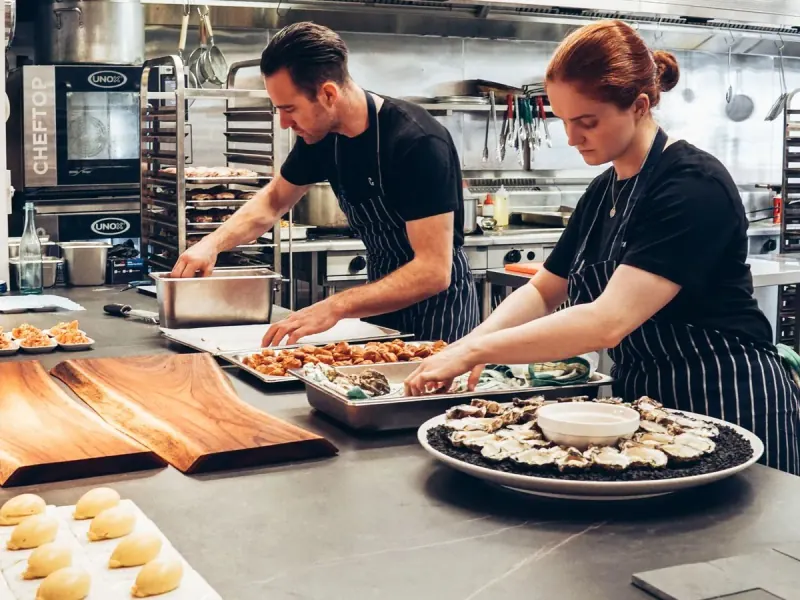 Deux personnes préparent des plats dans une cuisine de restaurant